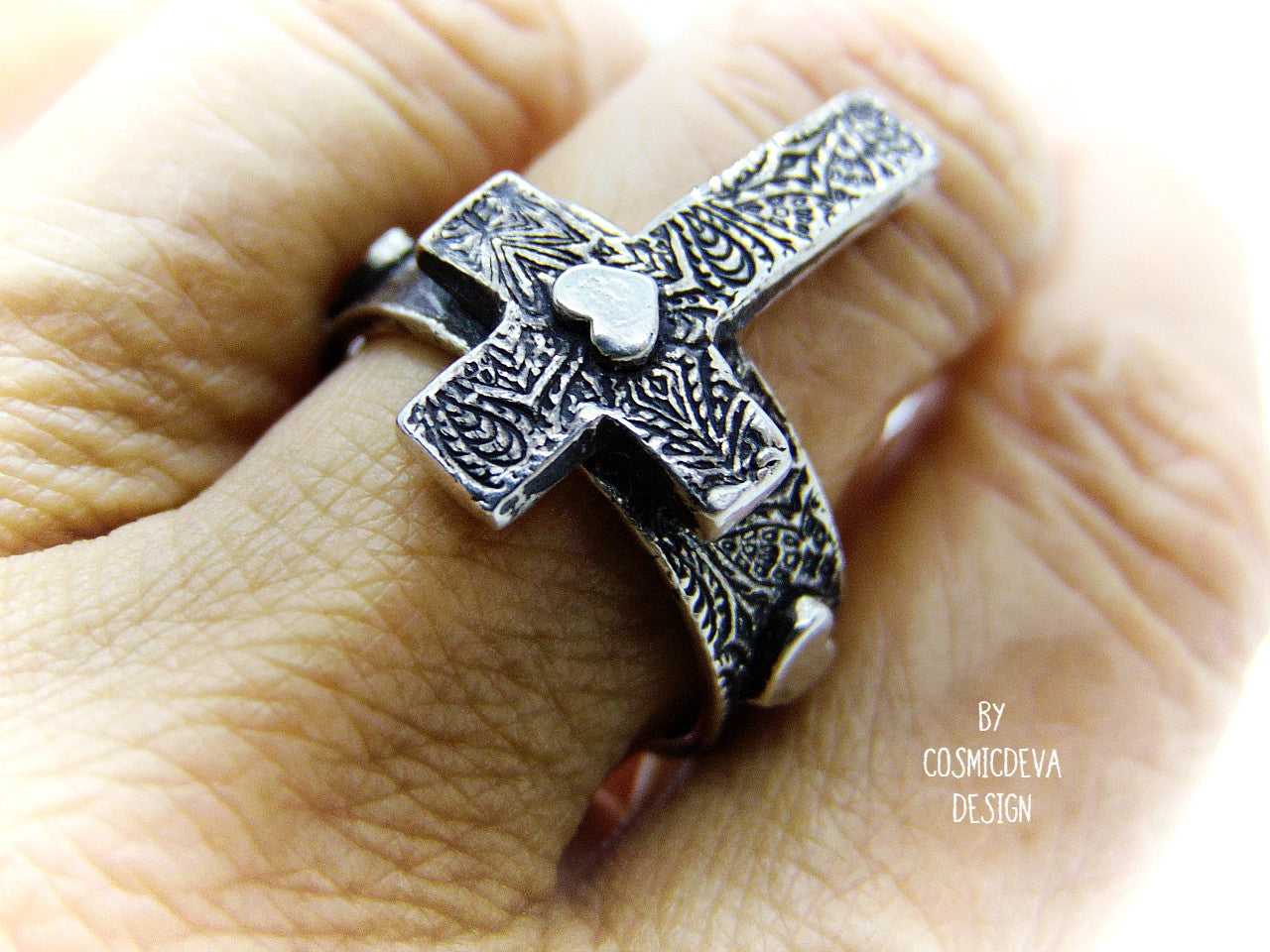 Completely handcrafted solid sterling silver cross ring. The surface of the ring features a rich oxidized textured cross with a heart in the center of the cross. The heart symbol in the center of the cross and on the sides of the ring shank is a reminder that Christ as a foundation is built on love – all the love we have for others should be unconditional in the same way he loves us. Love each other as I have loved you – John 15:12.