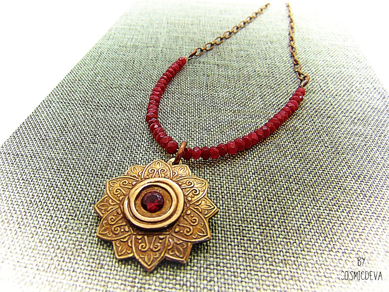 Celebrate your spiritual side with this unique Red Ruby Mandala Mendhi Gold Bronze Necklace. Crafted with a hand-formed bronze pendant, a stunning faceted lab-created ruby gemstone, and adorned with small red jade rondelle beads, this one of a kind necklace is an inspired homage to Indian Mehndi culture. Fall in love with the beauty and mystery of this spiritual accessory!