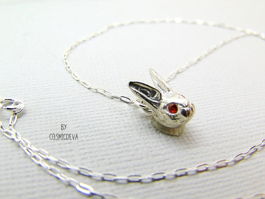 Handmade dainty small little rabbit 🐰 made of solid sterling silver with tiny faceted lab created fire opal eyes. Lab created stones are chemically, physically and optically identical to those mined underground. This cute little bunny dangles from a delicate 18 inch solid .925 sterling silver flat cable 1.4mm chain necklace.