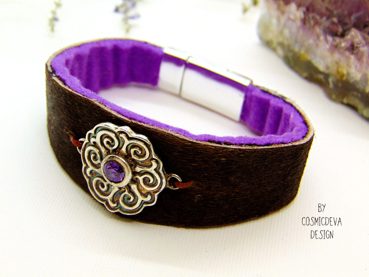 One of a kind handcrafted leather cuff bracelet made of hand cut earthy brown hair on cowhide leather. The focal point is a purple cubic zirconia amethyst in a bezel setting on a Celtic design textured solid 950 sterling silver disc. The inside of the leather bracelet is lined light purple/ lilac felt for your comfort. The handmade bracelet has silver colored stainless steel magnetic clasp which makes it easy to open and close.