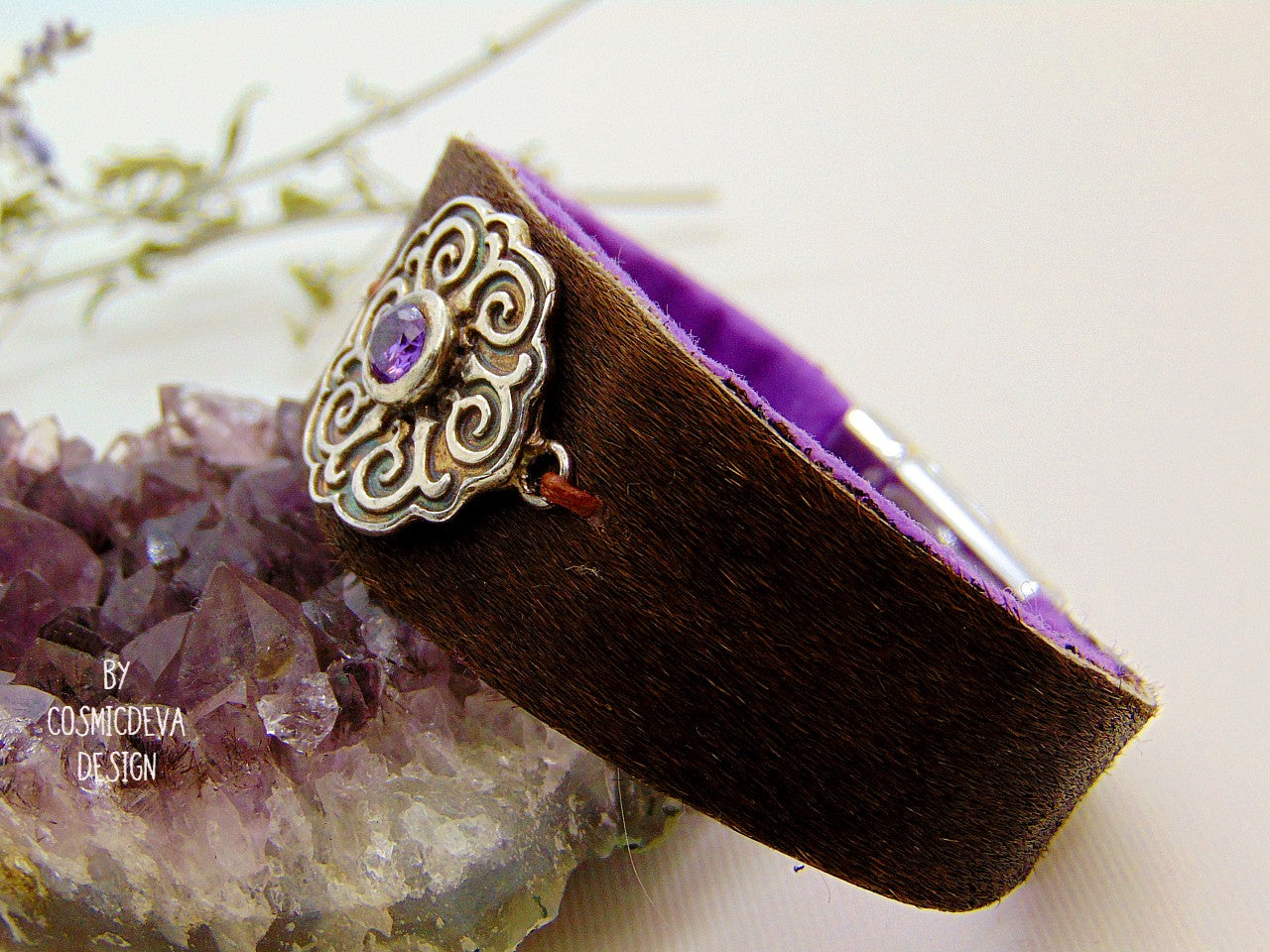 One of a kind handcrafted leather cuff bracelet made of hand cut earthy brown hair on cowhide leather. The focal point is a purple cubic zirconia amethyst in a bezel setting on a Celtic design textured solid 950 sterling silver disc. The inside of the leather bracelet is lined light purple/ lilac felt for your comfort. The handmade bracelet has silver colored stainless steel magnetic clasp which makes it easy to open and close.