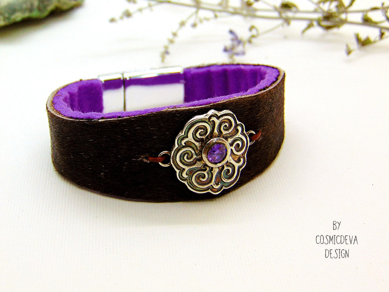 One of a kind handcrafted leather cuff bracelet made of hand cut earthy brown hair on cowhide leather. The focal point is a purple cubic zirconia amethyst in a bezel setting on a Celtic design textured solid 950 sterling silver disc. The inside of the leather bracelet is lined light purple/ lilac felt for your comfort. The handmade bracelet has silver colored stainless steel magnetic clasp which makes it easy to open and close.