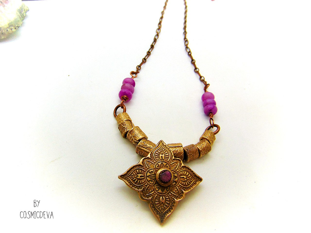 This unique spiritual yoga meditation necklace features a hand formed bronze mandala pendant with a beautiful natural pink tourmaline gemstone as a focal point. This Indian inspired mehndi mandala pendant suspends from a copper/brass chain with beautiful handcrafted gold bronze tube beads and lovely pink jasper gemstone rondelle beads.