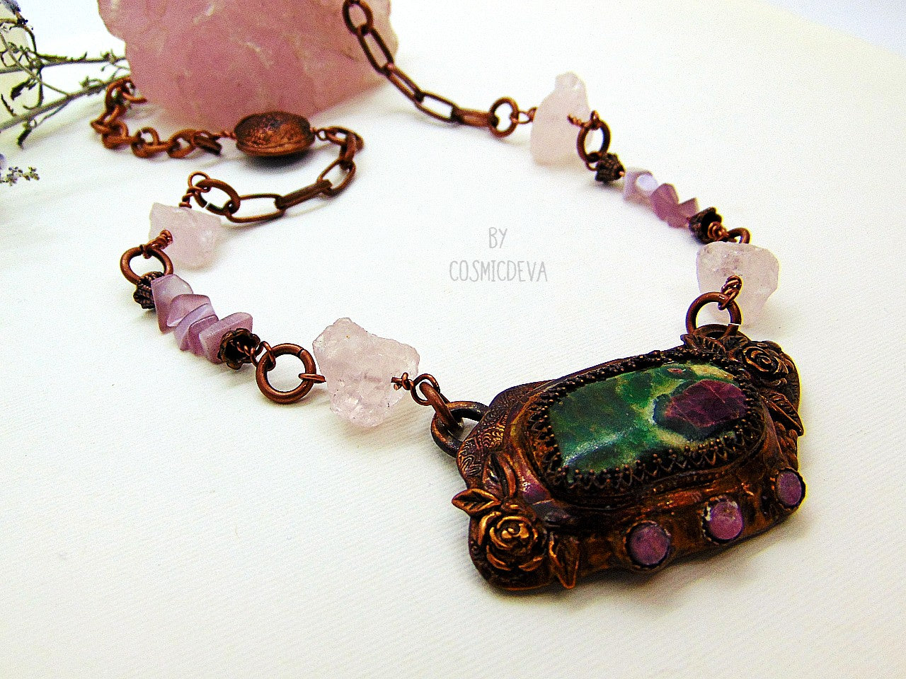 One of a kind handmade necklace with a hand sculptured solid copper pendant featuring a beautiful ruby in fuchsite gemstone cabochon in a bezel setting, surrounded with roses and natural raw pink tourmaline gemstones. This ruby in fuchsite statement necklace pendant suspends from a copper chain with accentual raw rose quartz crystal gemstones and handcrafted copper lentil beads.