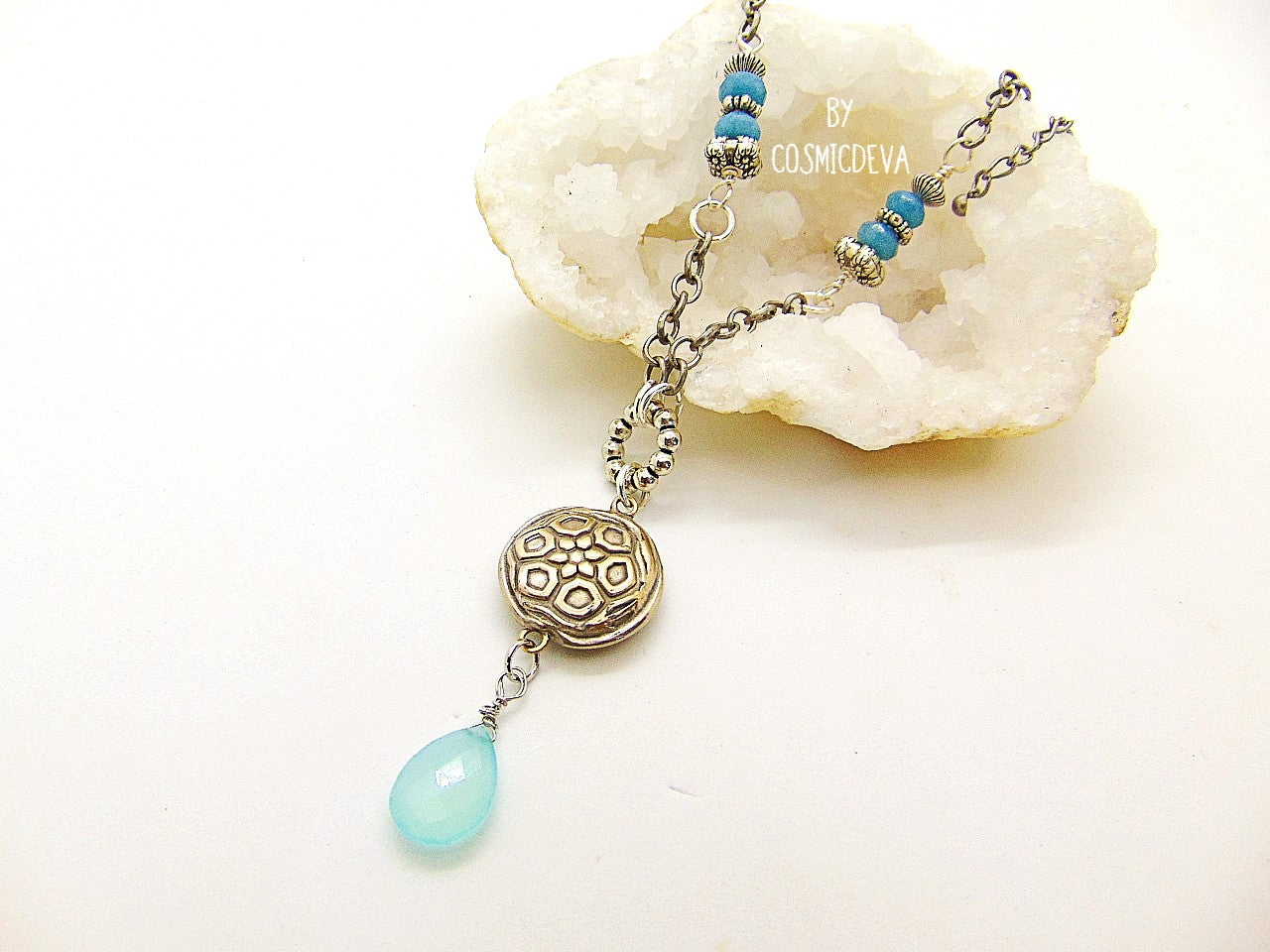 Beautiful handmade silver bronze lentil pendant with a mandala texture and a large faceted briolette aqua blue chalcedony gemstone dangle bead. The large hand formed lentil bead is double sided with two different designs and so can be worn facing either side.  The pendant suspends from an 18 inch – 20-inch-long chain with accentual faceted Brazilian aquamarine abacus beads and Tibetan silver beads.