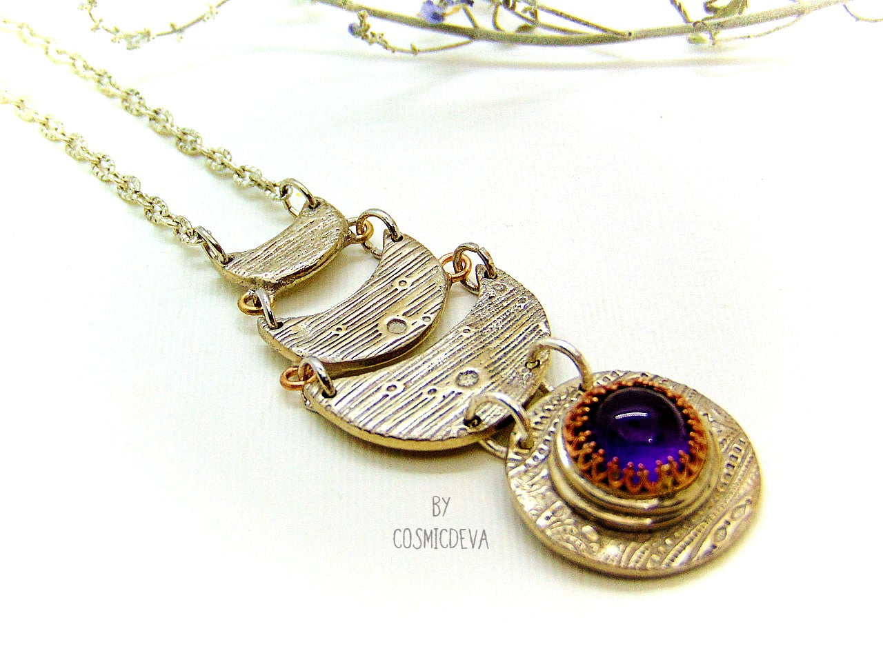 Beautiful purple silver moon phase necklace with a natural amethyst cabochon as a focal point. This silver bronze crescent moon pendant was completely hand formed and kiln fired. Silver bronze has the look of sterling silver but for a more affordable price. The moon pendant suspends from an 18 inch – 20-inch-long chain.