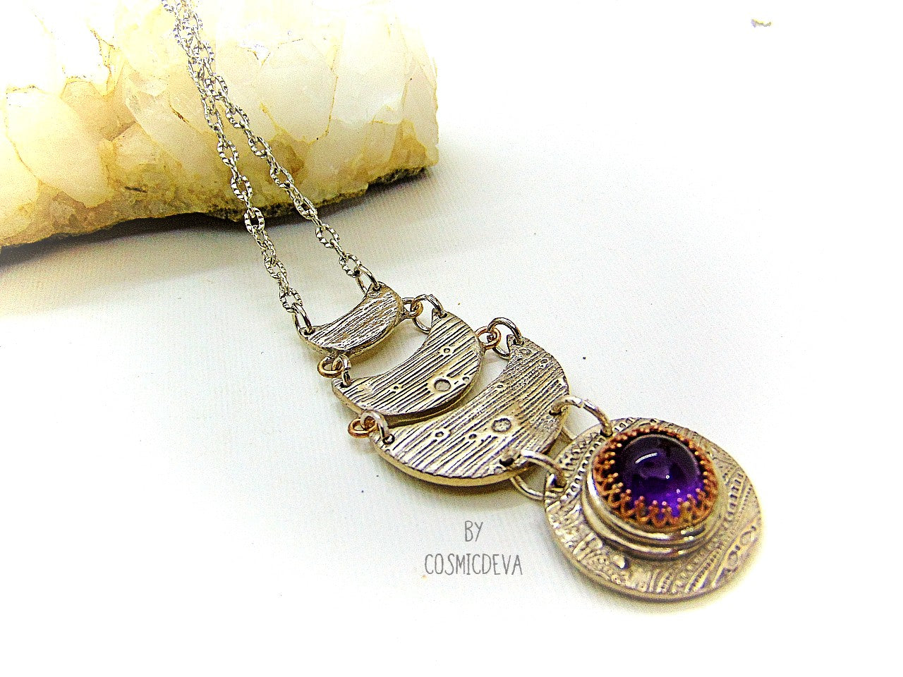 Beautiful purple silver moon phase necklace with a natural amethyst cabochon as a focal point. This silver bronze crescent moon pendant was completely hand formed and kiln fired. Silver bronze has the look of sterling silver but for a more affordable price. The moon pendant suspends from an 18 inch – 20-inch-long chain.