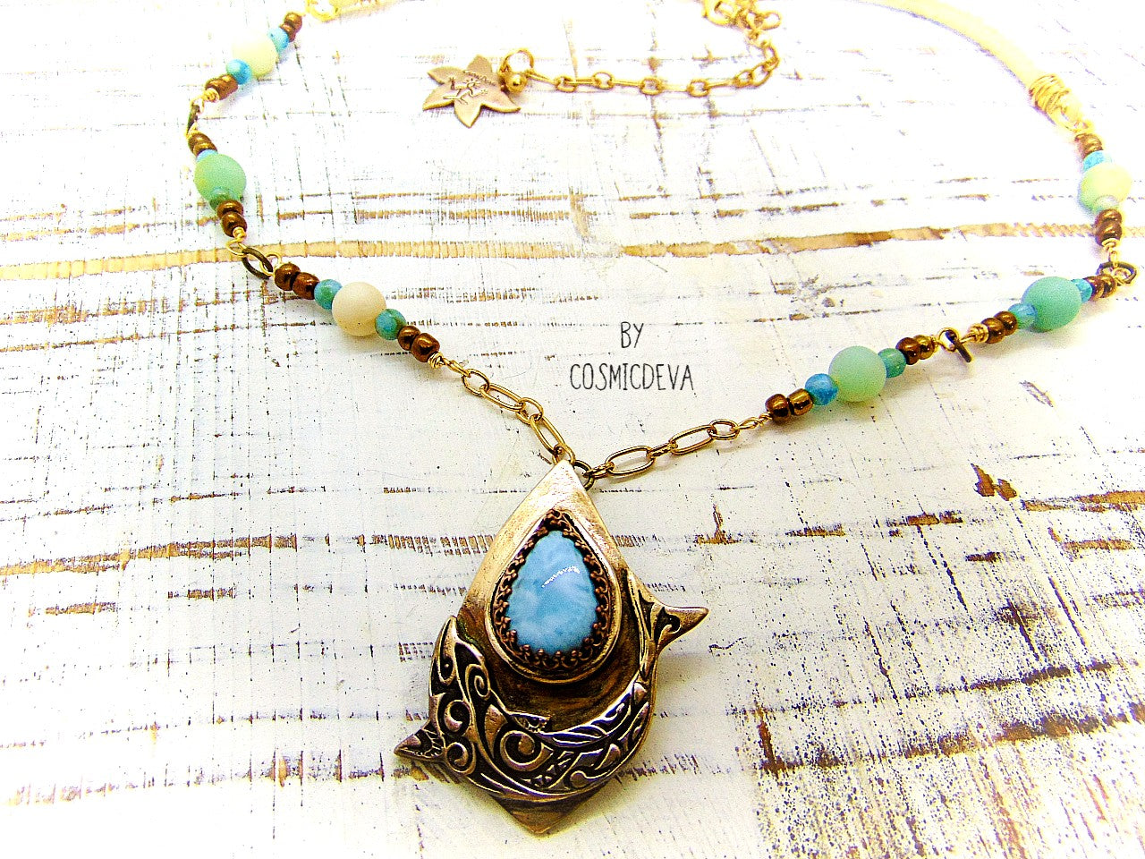 Bring harmony to your life with this beautiful Dolphin Spirit Animal Larimar Bronze Necklace. Handcrafted from solid bronze and adorned with a larimar gemstone, this one-of-a-kind pendant symbolizes the wisdom of Atlantis and healing power of dolphins - sure to bring peace and balance to your life. Finished with white leather and aqua colored jasper and amazonite gemstone beads.