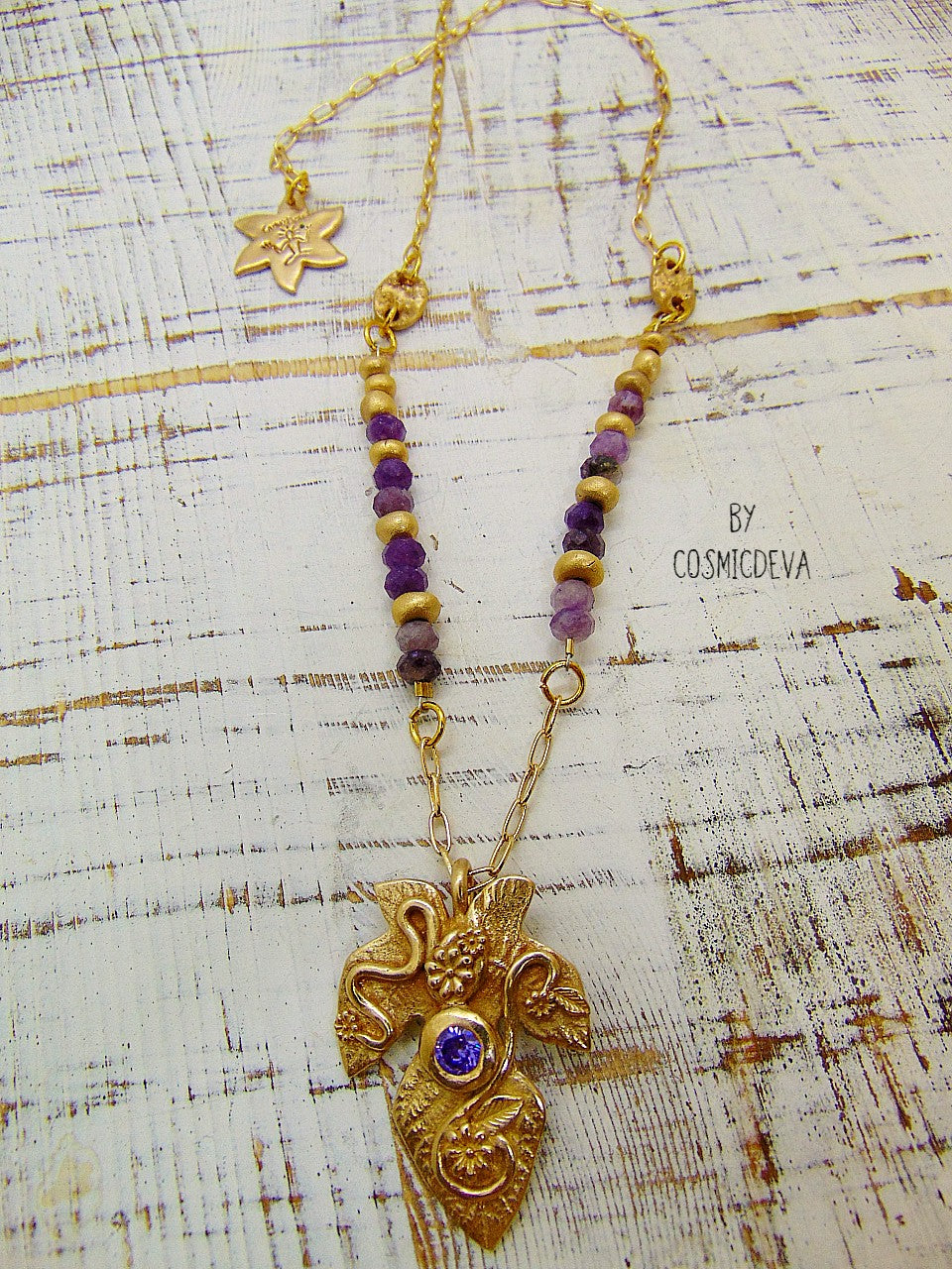 Playful handcrafted fig leaf with an Amethyst in the center and adorned with flowers and swirls. The dainty 18–21-inch necklace is strung with small facetted raw natural lepidolite gemstone rondelle beads and hand formed gold bronze pearls and connectors. I created and casted this leaf with a small fig tree leaf from our garden.