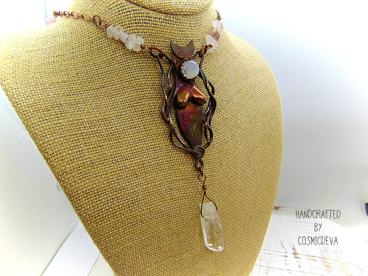 Lovely one-of-a-kind hand sculptured solid bronze organic primitive female divine energy goddess pendant featuring a moonstone and a dangling clear quartz crystal point. The pendant was oxidized to create this beautiful shimmering color tones. The handcrafted copper chain necklace features clear white quartz crystals and rose quartz.