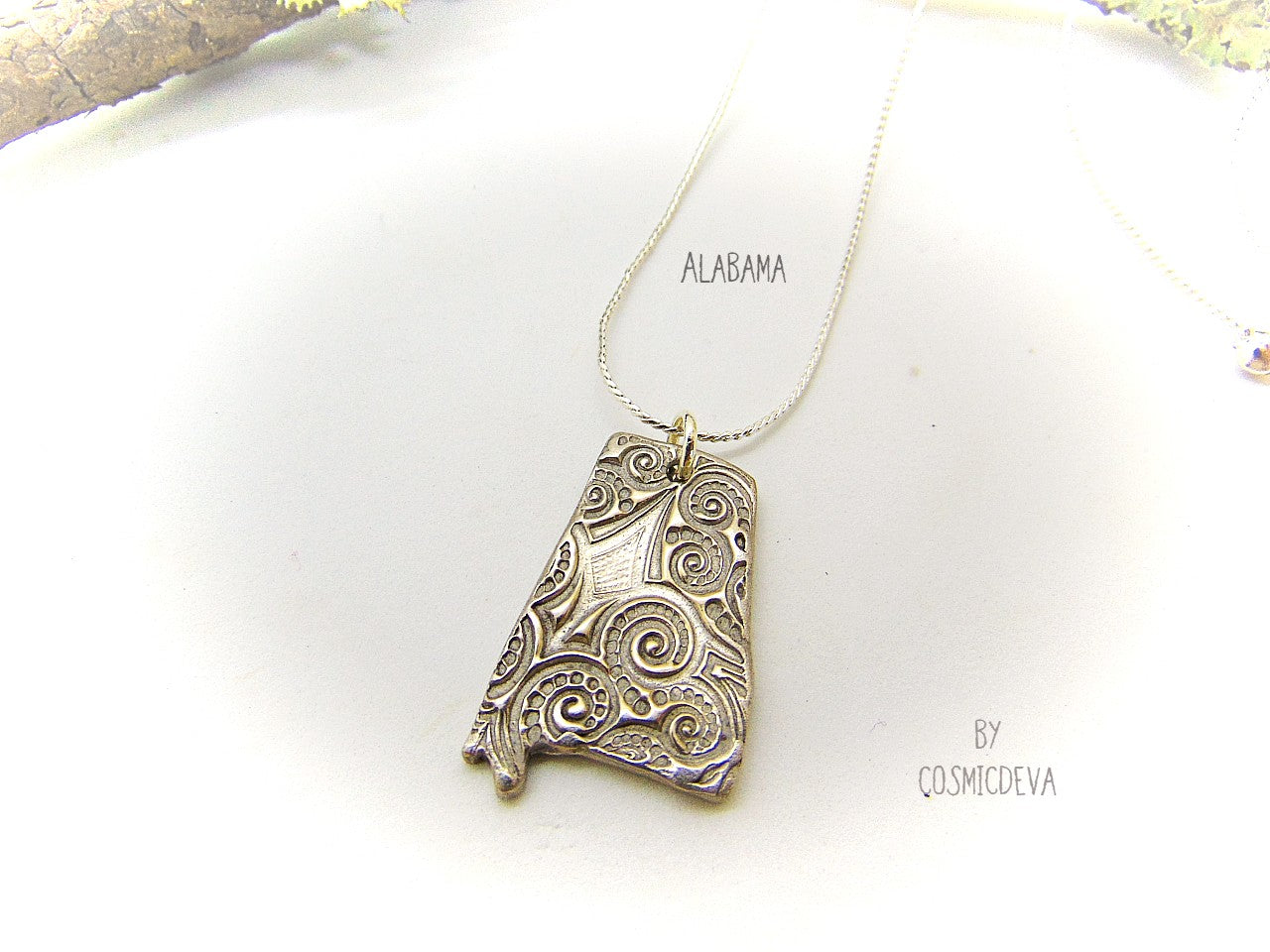 handcrafted and kiln fired Alabama State shaped pendant made of silver bronze.  This Alabama pendant dangles from a 20-inch silver plated chain.  The backside of the pendant is signed by CosmicDeva.